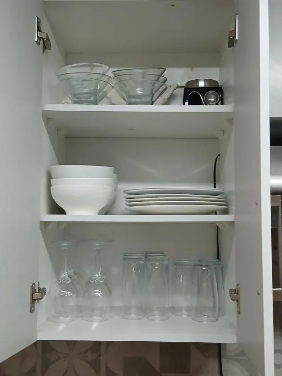 Open kitchen cabinet displaying glassware, dishes, and serving items neatly organized