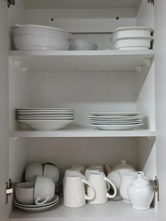 White crockery and dishes neatly organized in kitchen cabinet shelves