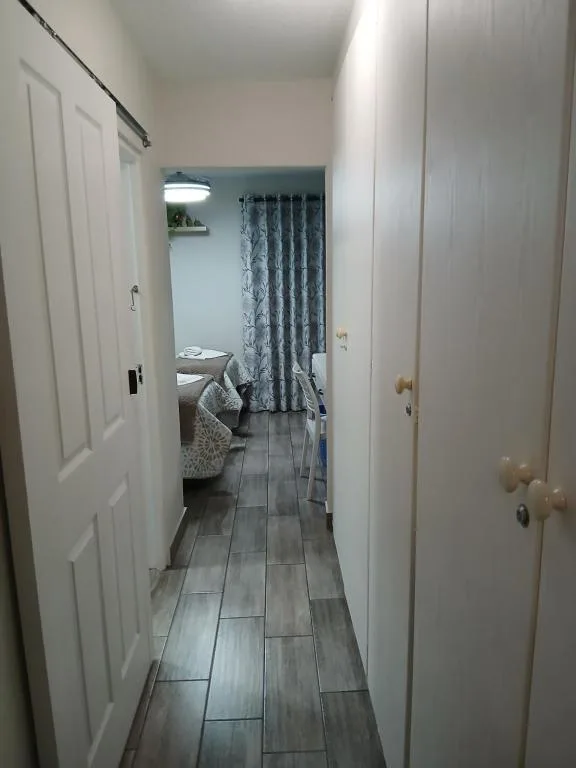 Hallway with dark tile flooring leading to bedroom with patterned curtains