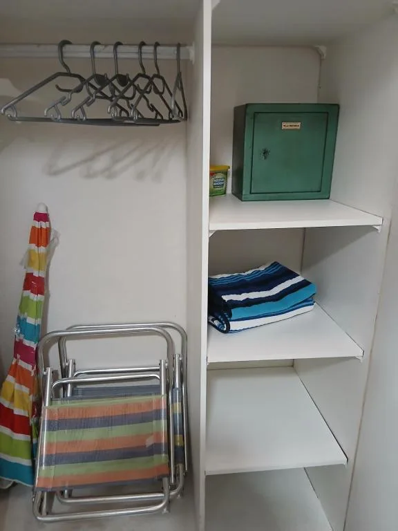 Closet interior with hangers, beach chairs, towels, and storage shelves