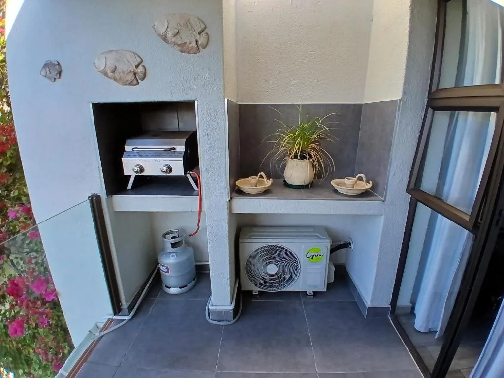Outdoor alcove with built-in braai, gas bottle, air conditioning unit, and decorative elements
