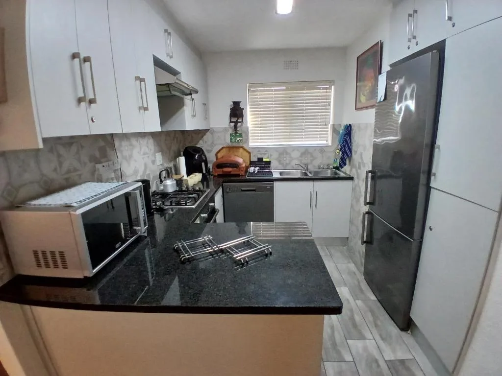 Modern kitchen with white cabinetry, dark countertop, gas stove, and stainless steel appliances