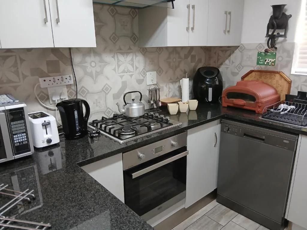 Modern kitchen with gas stove, dark countertops, white cabinetry, and appliances