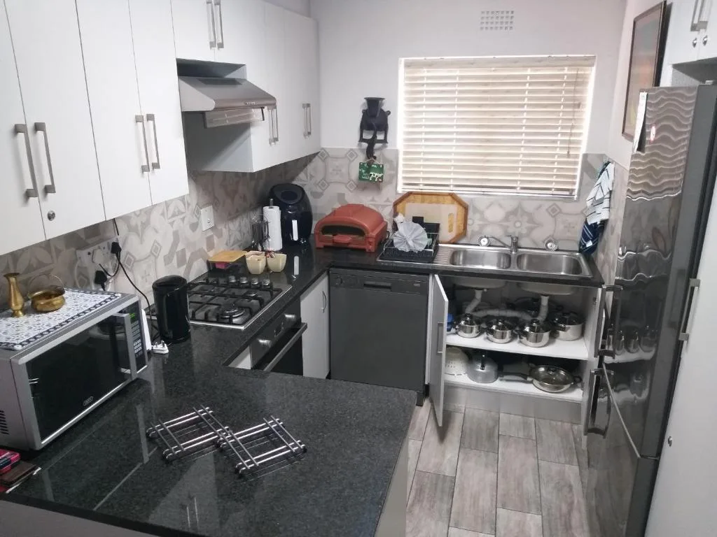 Modern kitchen with gas stove, sink, dishwasher, and dark countertops