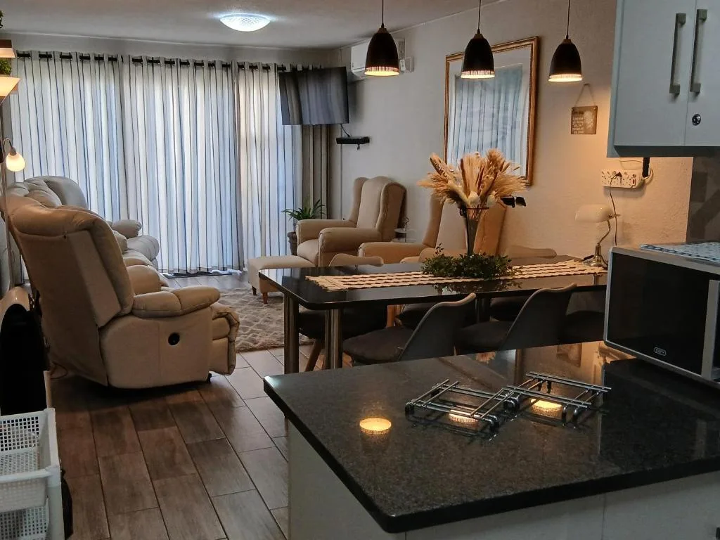 Open-plan lounge with recliners, dining table, and kitchen view