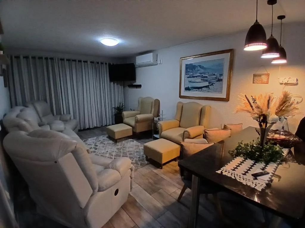 Spacious lounge with cream armchairs, pendant lights, and coastal artwork