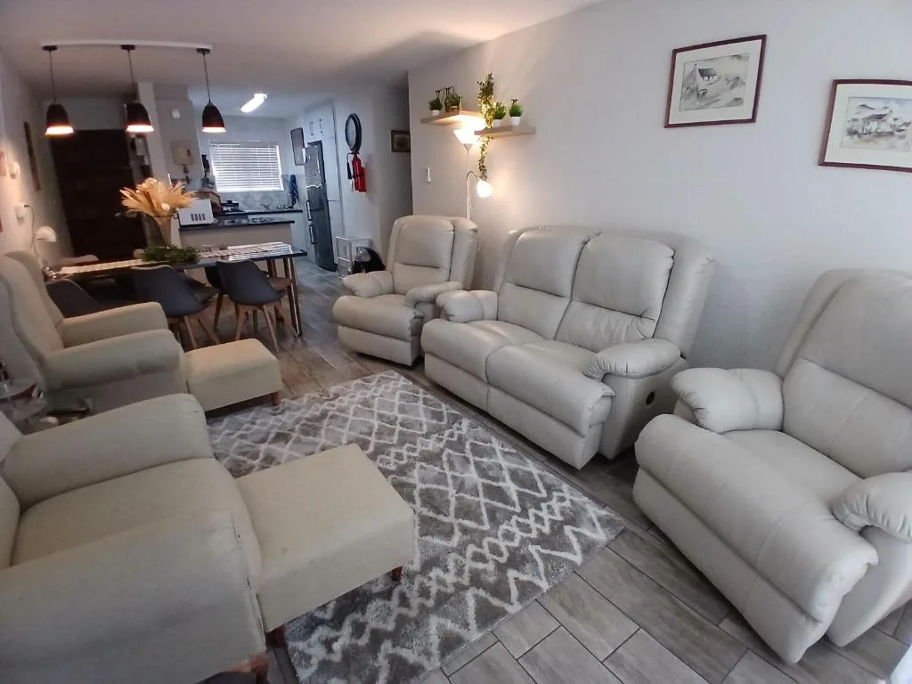 Modern living room with cream recliners, geometric rug, and pendant lighting