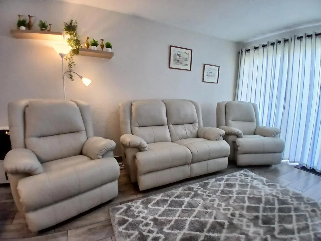 Spacious lounge with reclined seating, plants, and garden views