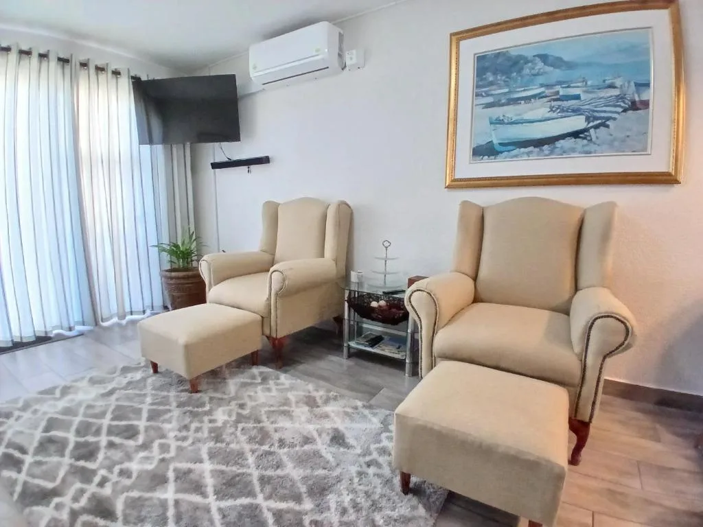 Bright lounge with cream wingback chairs, TV, and coastal artwork on walls