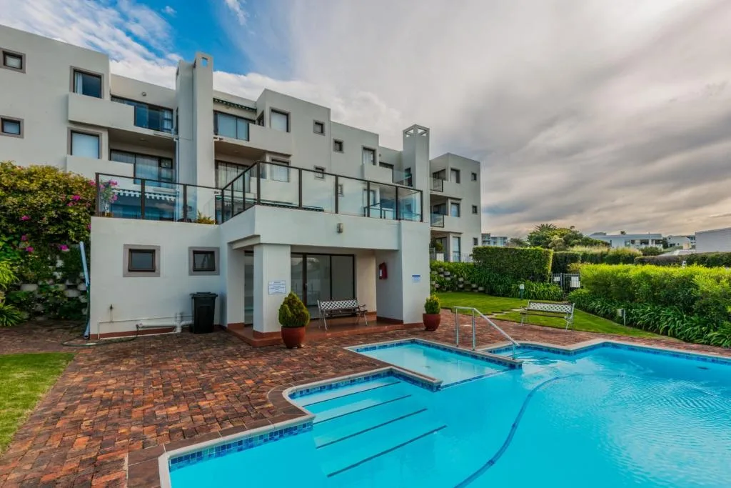 Bright blue swimming pool with diving board in front of modern apartment building