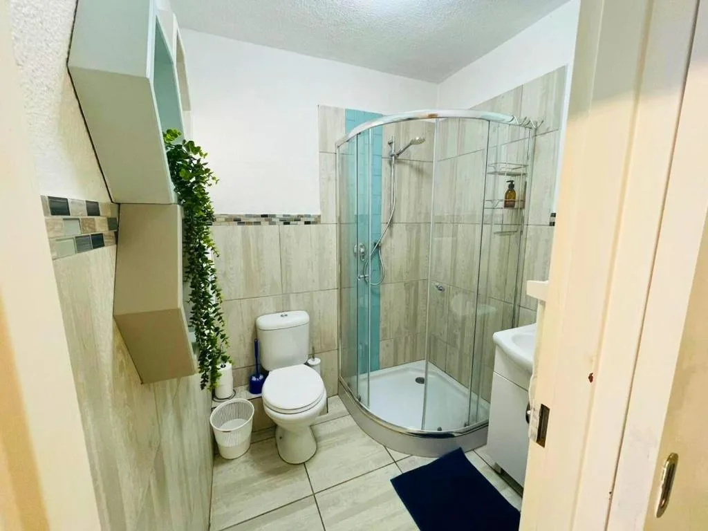 Modern bathroom with curved glass shower enclosure and white toilet fixtures