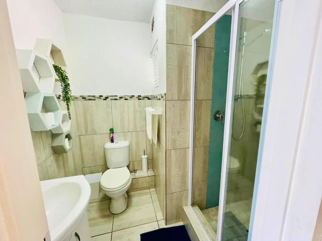 Modern bathroom with toilet, sink, shower cubicle, and tiled walls