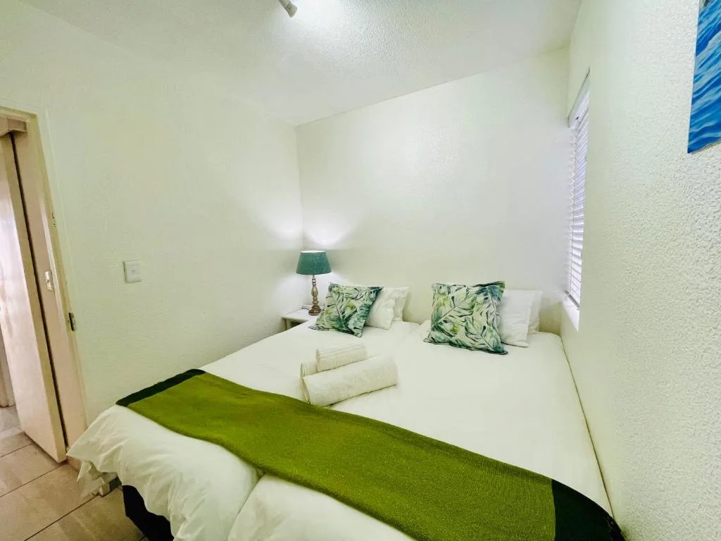 Bright bedroom with queen bed, green accents, and fresh white linens