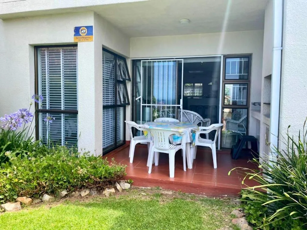Patio area with white table, chairs, and garden surroundings