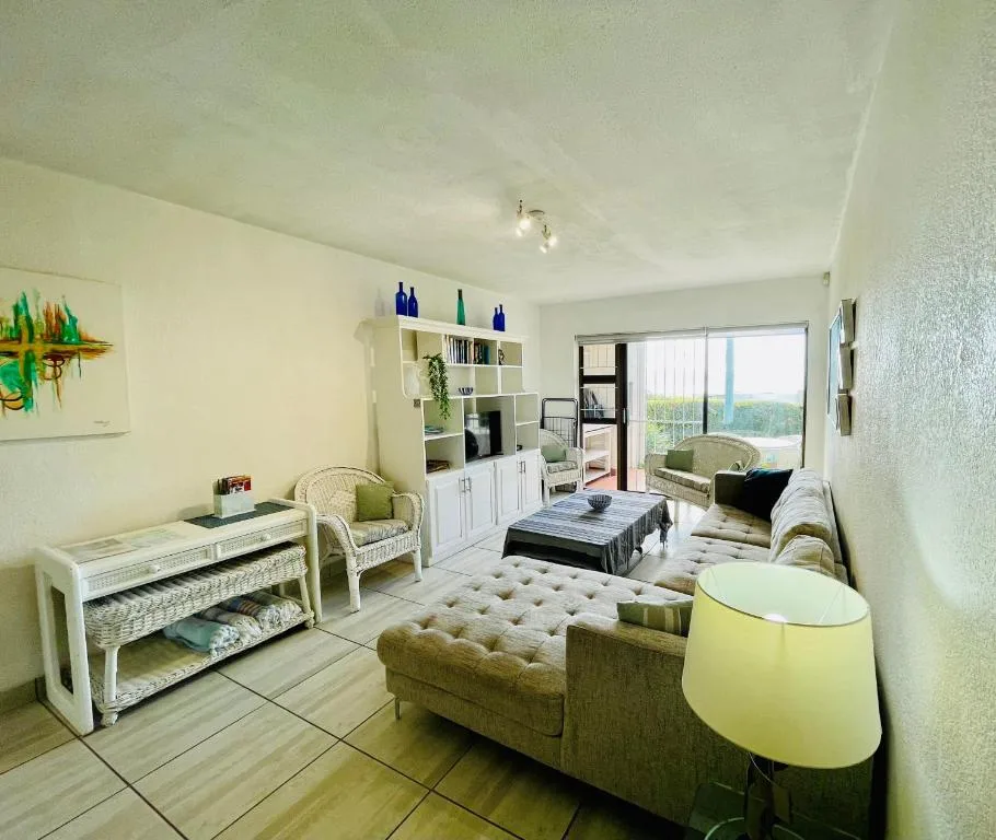 Bright open-plan lounge with comfortable seating and lagoon views beyond