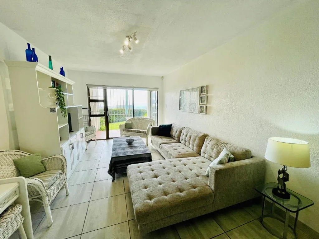 Bright lounge with cream sectional sofa, deck views, and modern furnishings