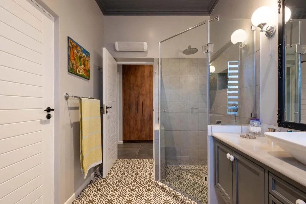 Modern bathroom with walk-in shower, double vanity sink, and patterned tile flooring