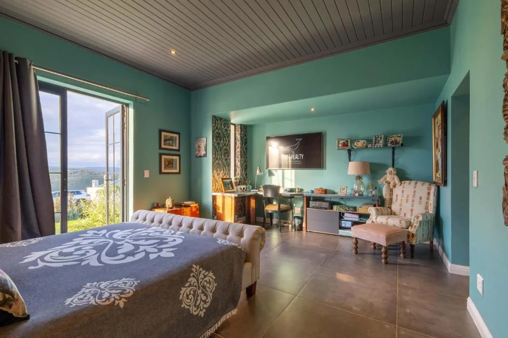 Spacious turquoise bedroom with bed, desk area, and scenic mountain view windows
