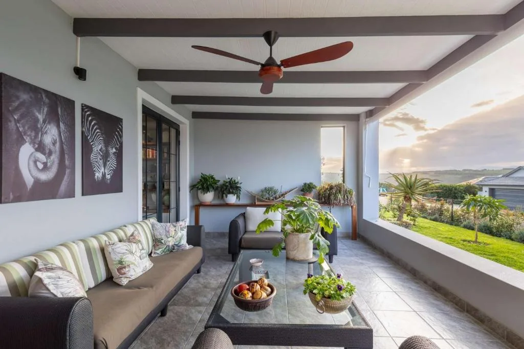 Covered patio with seating, plants, and expansive views of green landscape