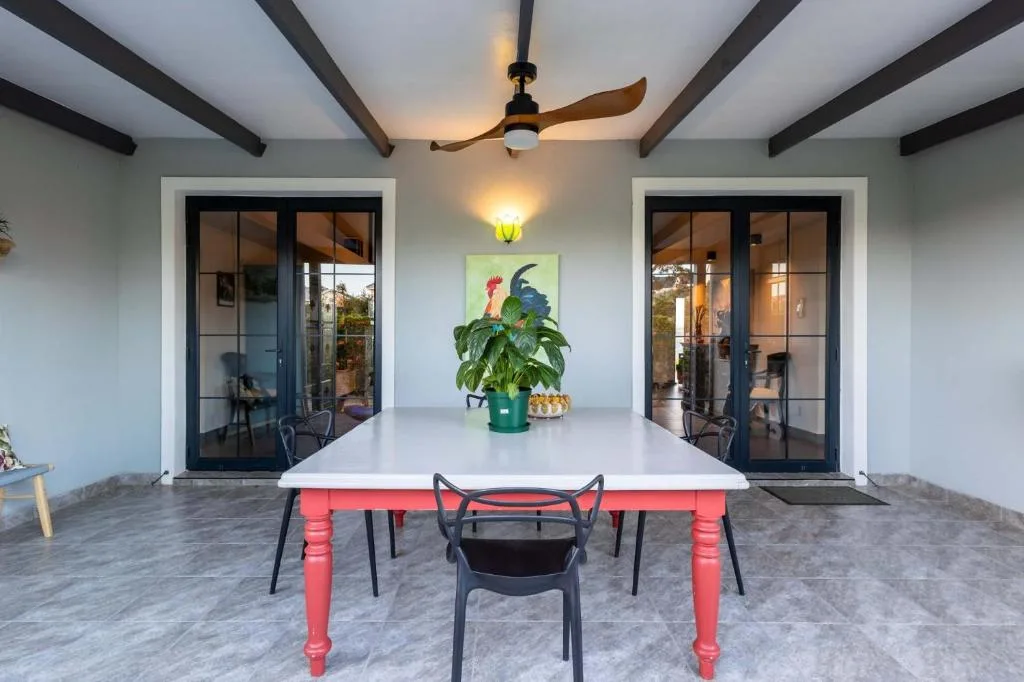 Covered outdoor dining area with red table and black chairs