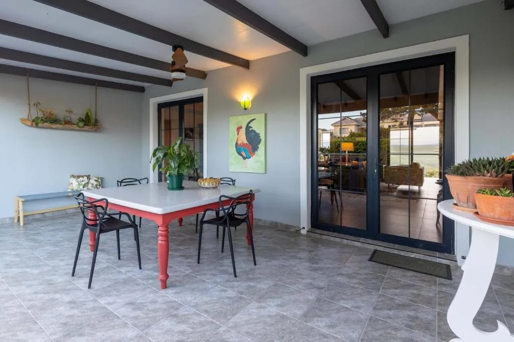 Covered patio with red dining table, black chairs, and garden views