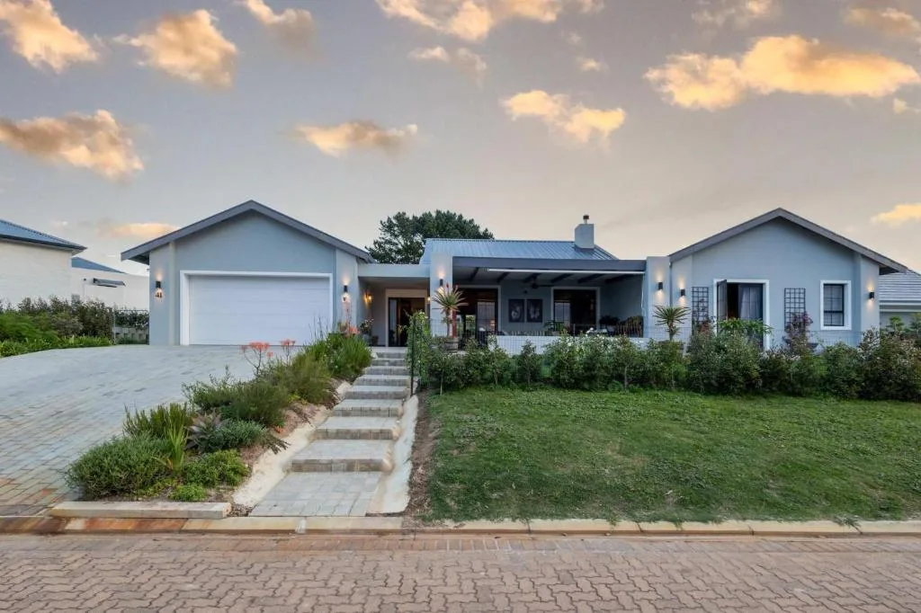 Modern white house with garage and manicured front garden at dusk