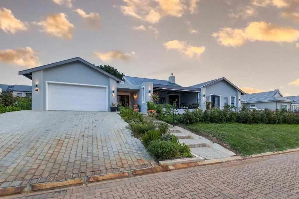 Modern light blue house with garage and manicured garden entrance at dusk