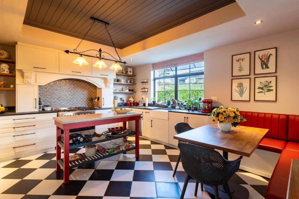 Spacious kitchen with cream cabinetry, red island, and dining area with red seating