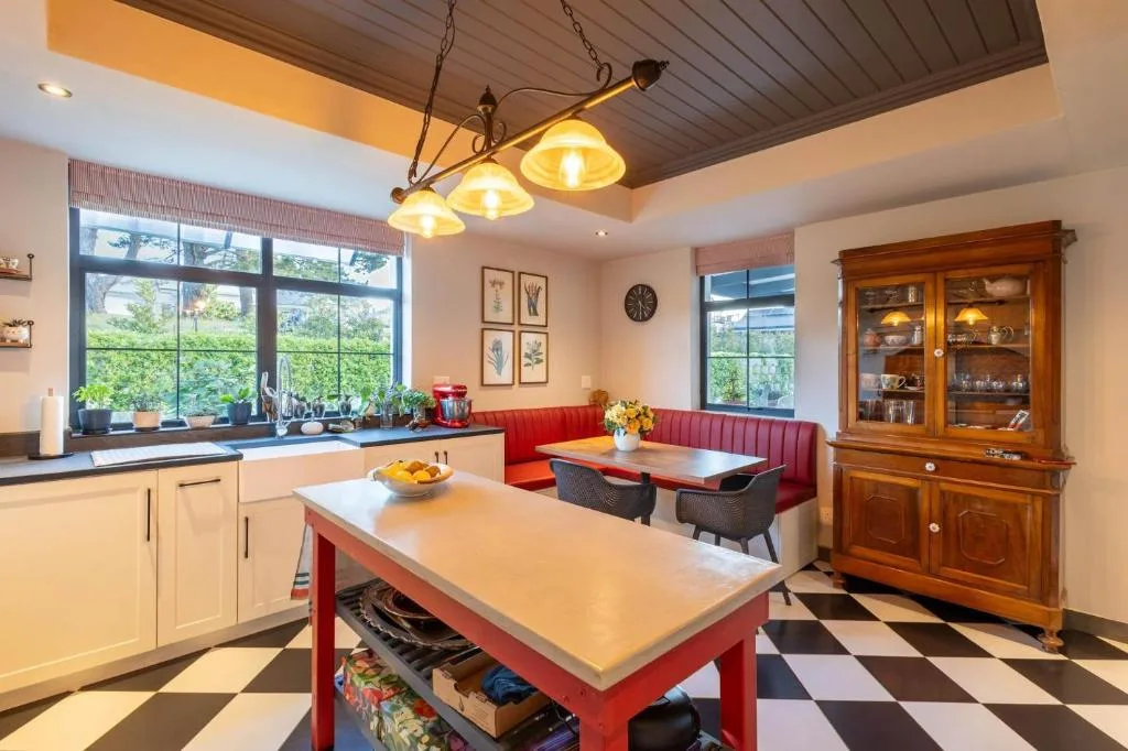 Open-plan kitchen with cream cabinetry, red island, and garden views