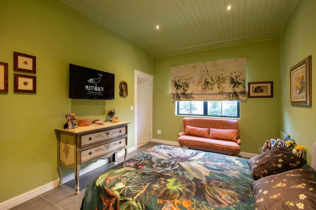 Bright green lounge with TV, colorful artwork, and orange seating bench