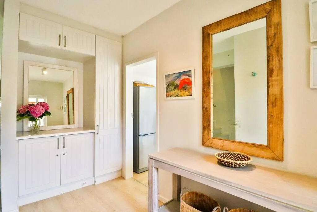 Spacious bathroom with dual vanities, wooden-framed mirror, and fresh flowers