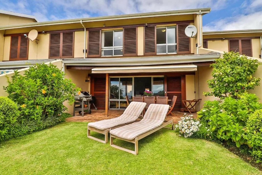 Garden patio with loungers, manicured lawn, and braai area