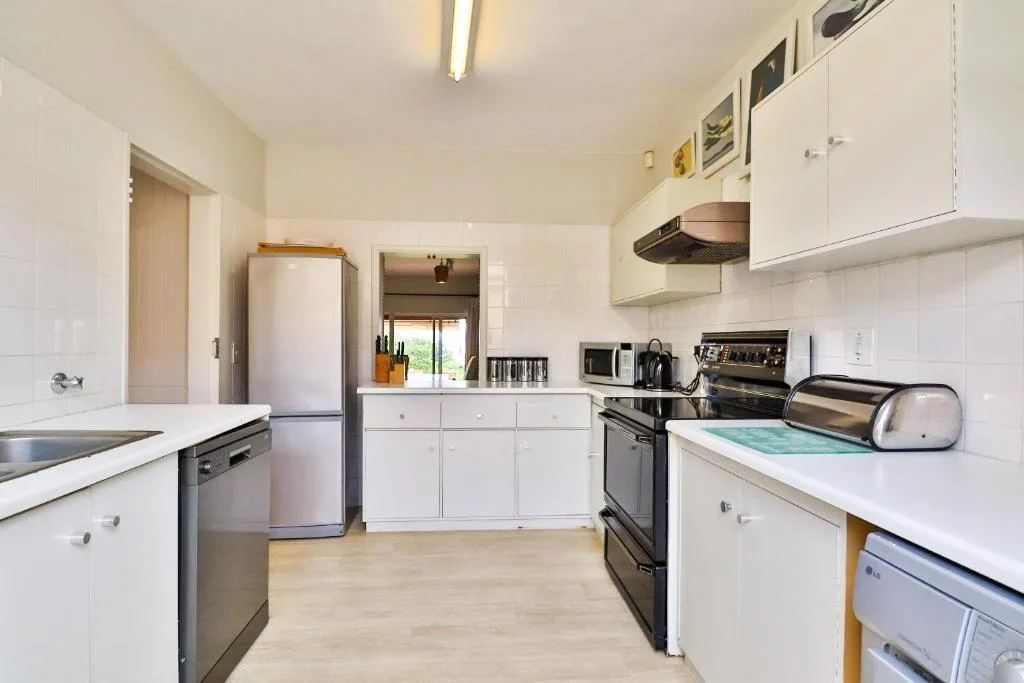 Bright kitchen with white cabinetry, stainless steel appliances, and wooden flooring