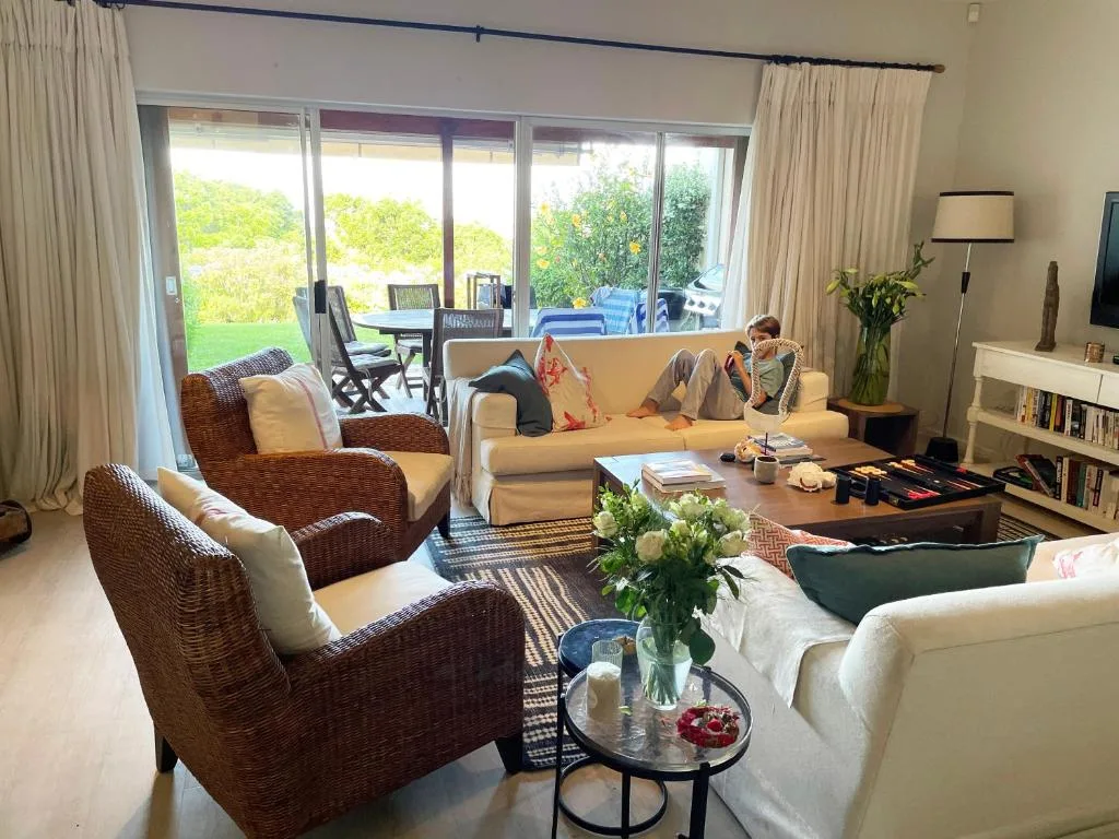 Spacious lounge with wicker chairs, cream sofa, and garden views through sliding doors