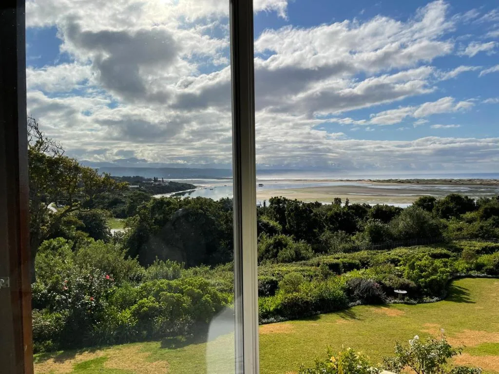 Scenic lagoon and coastal vista from large window overlooking lush gardens