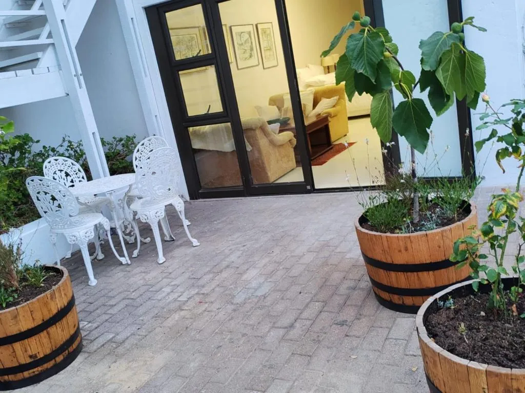 Paved patio with white chairs and planted barrel containers near building