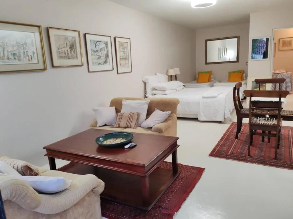 Spacious lounge with comfortable seating, wooden coffee table, and bed in background