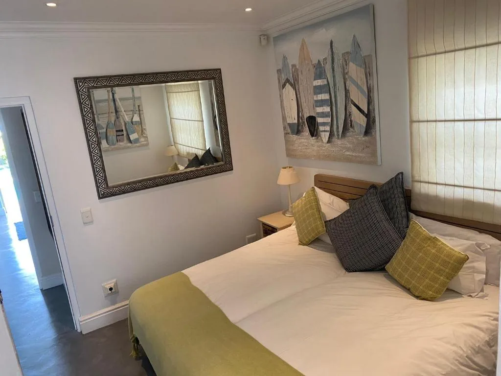 Bright bedroom with queen bed, decorative cushions, and coastal artwork