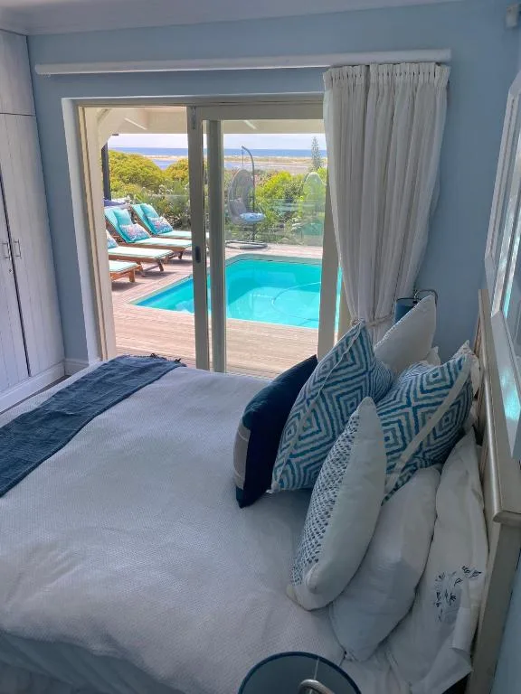 Bright bedroom with bed facing glass doors opening to pool and ocean view