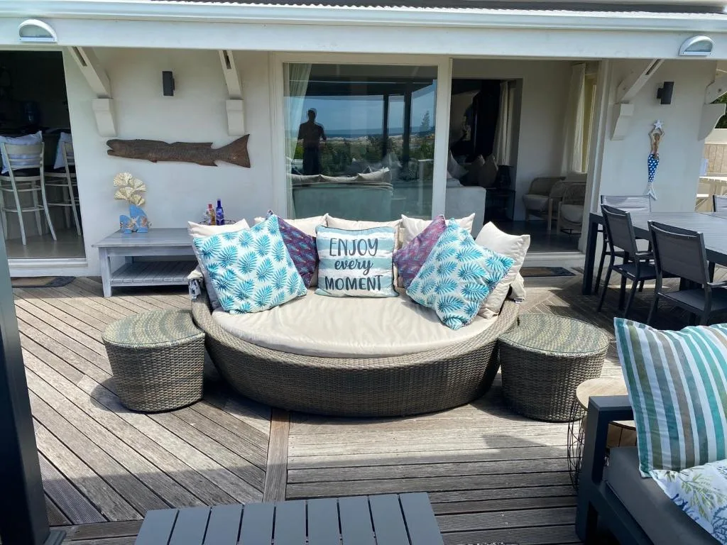 Curved outdoor daybed with cushions and decorative pillows on wooden deck