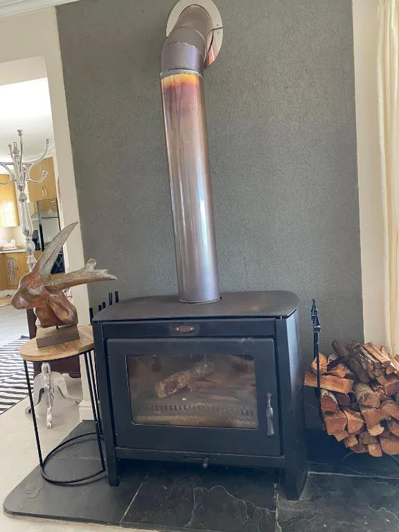 Modern wood-burning stove with tall chimney pipe and decorative wooden figurine