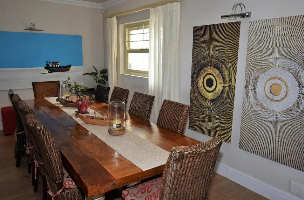 Dining room with wooden table, woven chairs, and decorative wall art