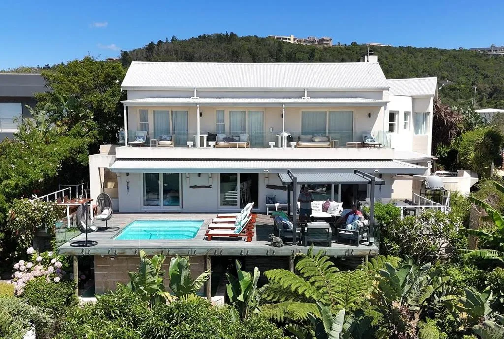 Modern white two-story holiday home with pool deck and garden landscaping