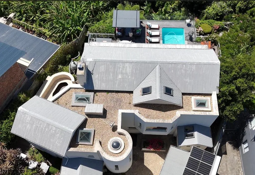 Aerial view of modern property with pool, deck, and manicured gardens