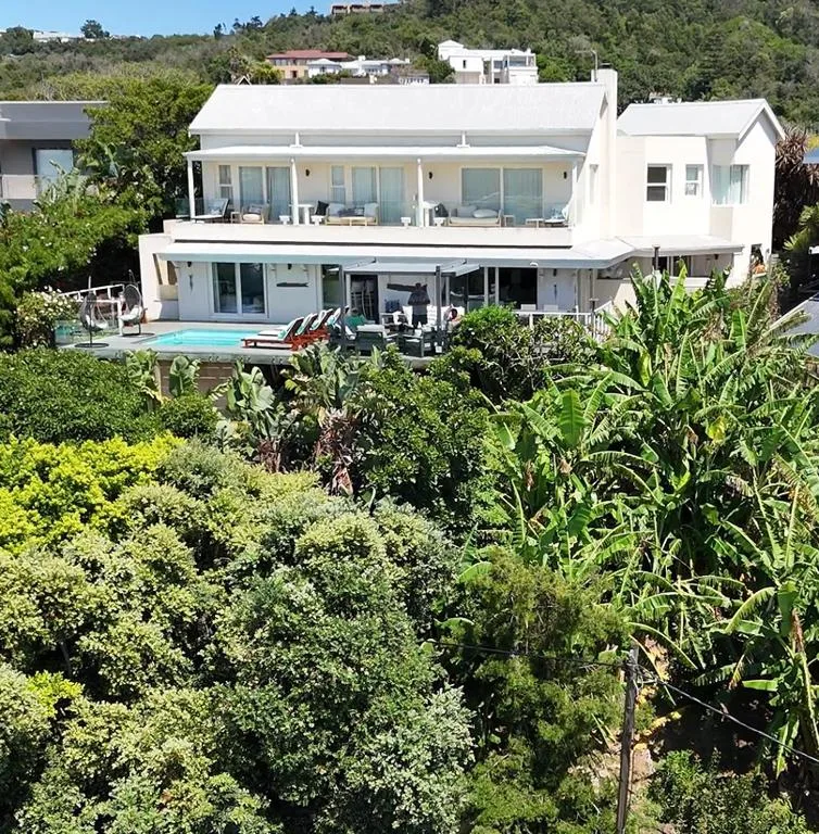 Modern white villa with pool, deck, and lush garden landscape
