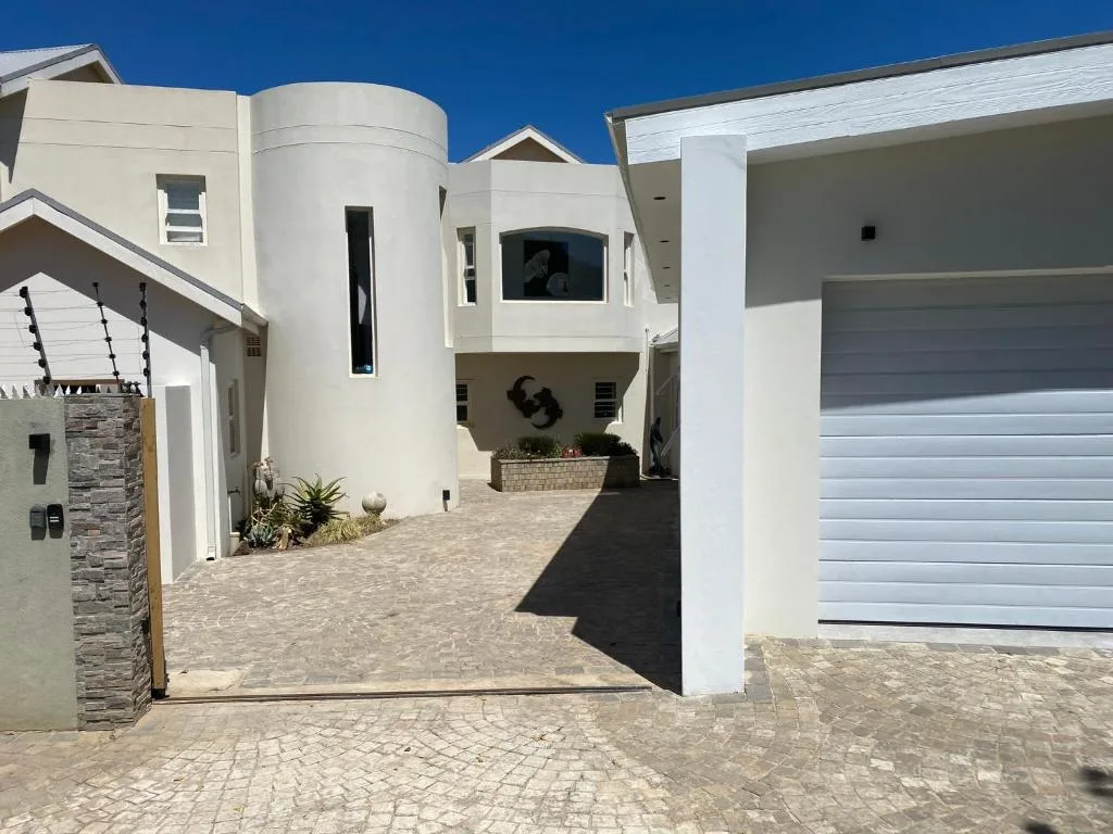 Modern white property facade with circular tower, driveway, and garage doors