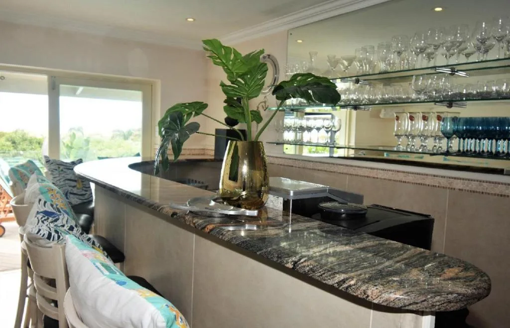 Modern kitchen with granite countertop, bar seating, and glassware shelving