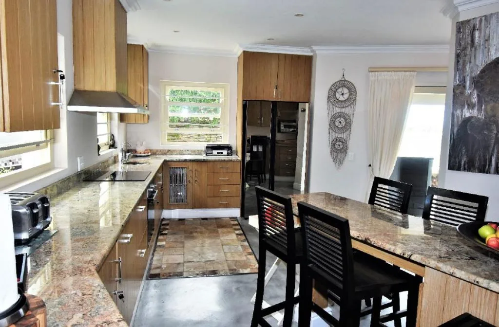 Modern kitchen with wooden cabinetry, granite countertops, and dining area seating