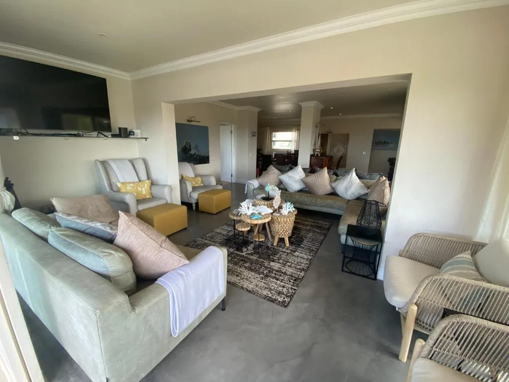 Spacious lounge with cream sofas, yellow accents, and flat-screen TV