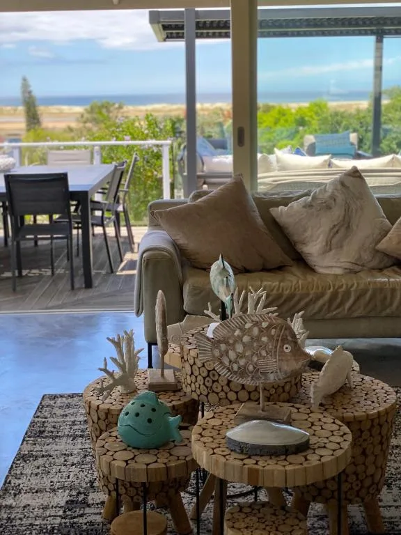 Spacious lounge with coastal views, sofa, decorative tables and ocean beyond